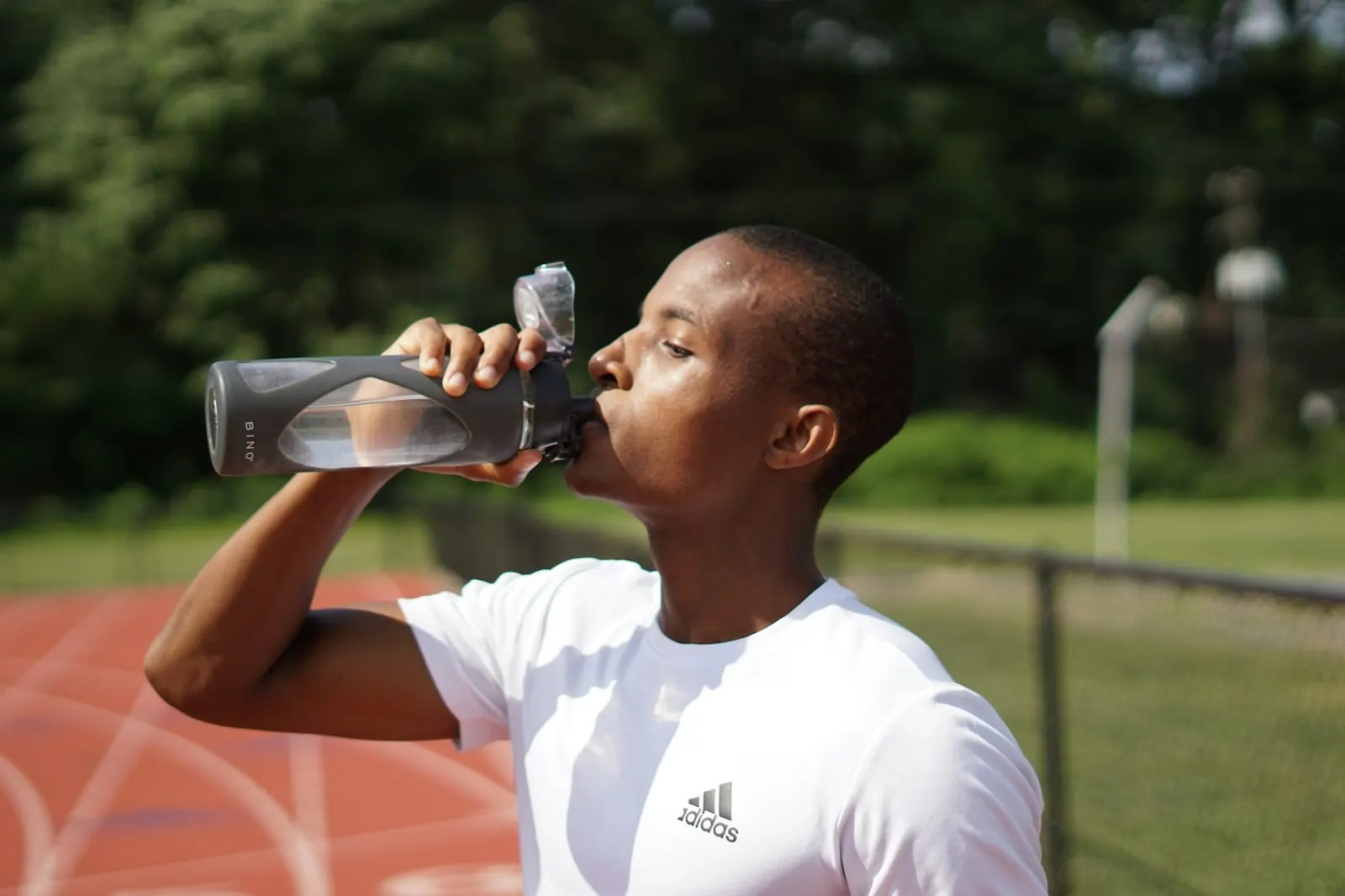 Coureur sur une piste d’athlétisme qui boit à une gourde après l’effort