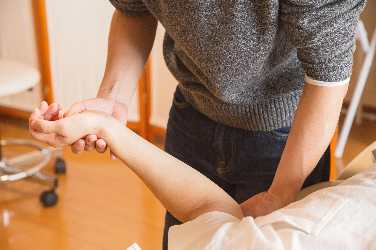 Praticien qui mobilise le bras d’un patient allongé
