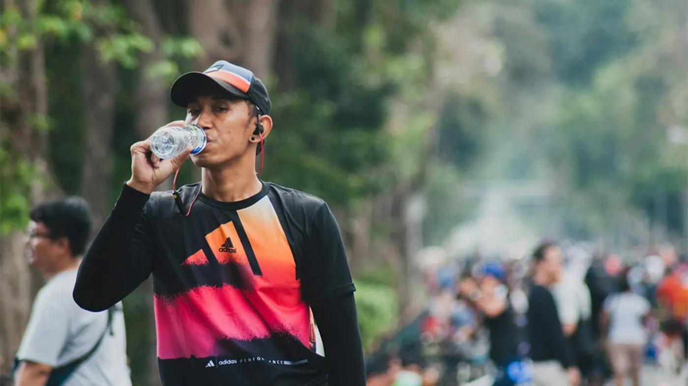 Coureur qui boit à une bouteille pendant une course