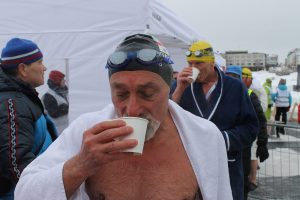 nageur en eau froide qui boit une boisson chaude à la sortie