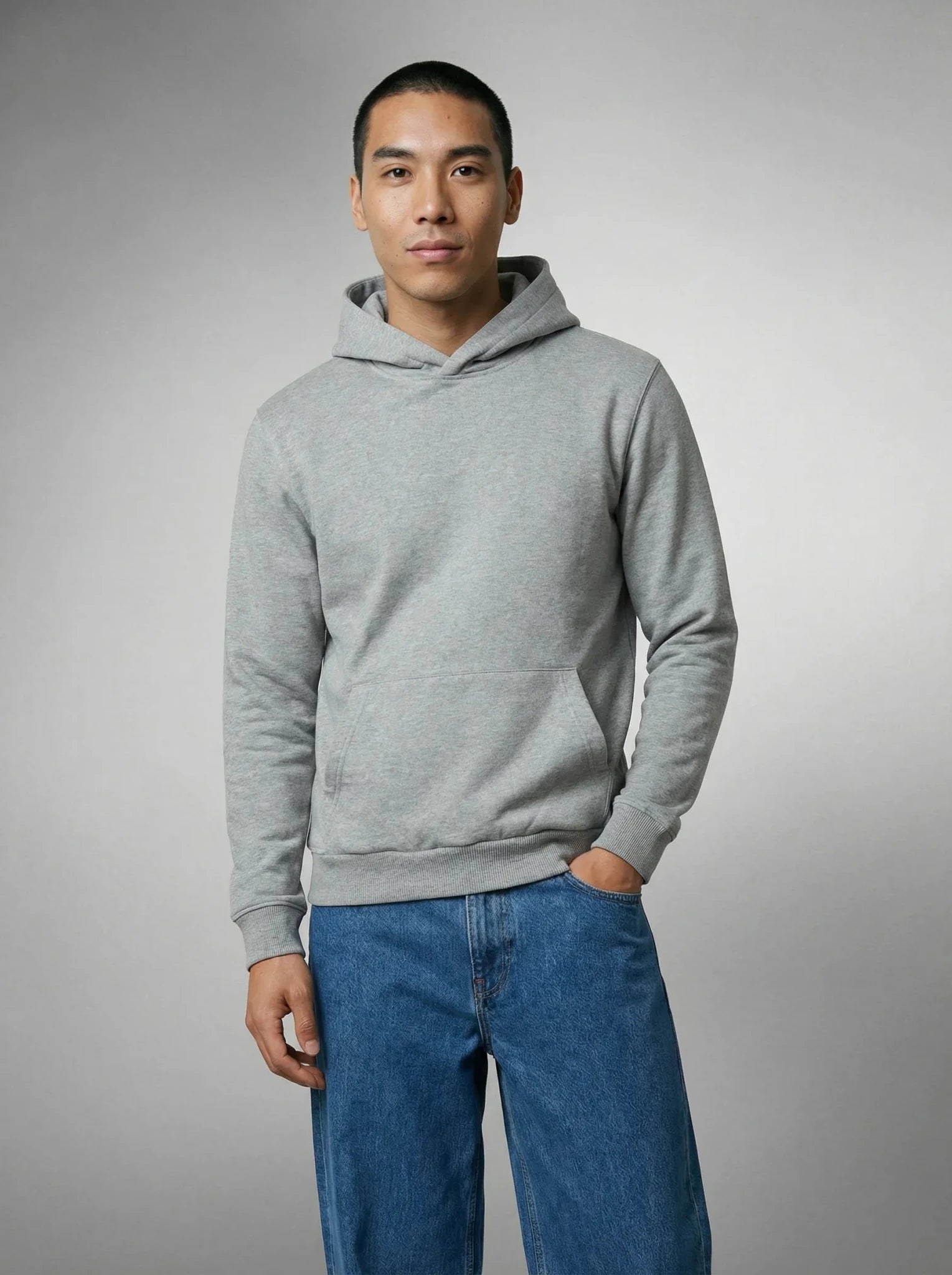 Homme en sweat à capuche gris, main dans la poche, jean bleu